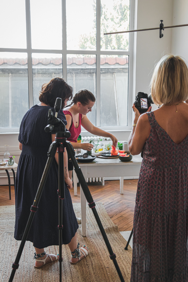 Des participants à un workshop de photographie culinaire composent une scène autour d'un cocktail