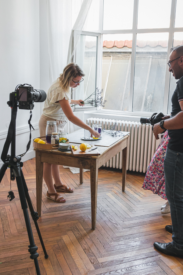 Une participante à un atelier photo crée une scène autour d'un cocktail sur une belle table en bois